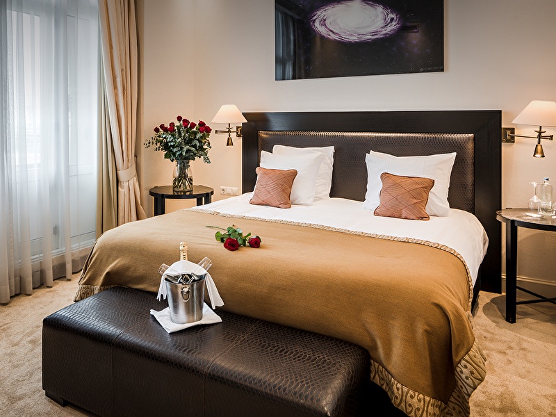 Atmospheric hotel room with romantic details, roses in the corner, roses on the bed, and a bottle of champagne with two glasses